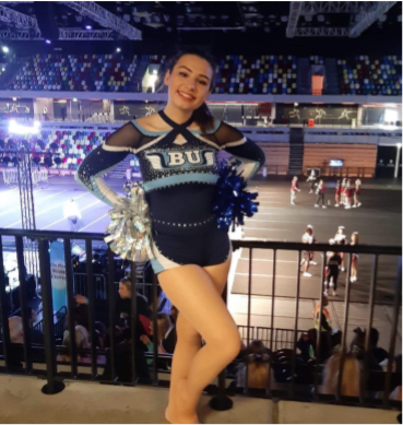 Gemma posing in her cheerleading uniform at a college rally.